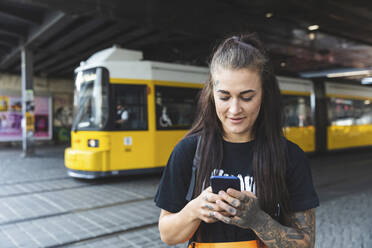Portrait of tattooed young woman text messaging, Berlin, Germany - WPEF02367