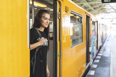 Portrait of tattooed young woman getting out of elevated railway, Berlin, Germany - WPEF02380