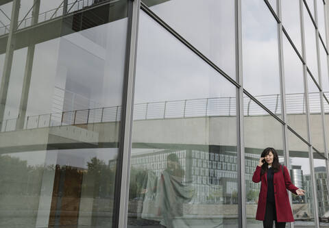 Geschäftsfrau steht in der Nähe eines modernen Gebäudes und benutzt ein Smartphone, lizenzfreies Stockfoto
