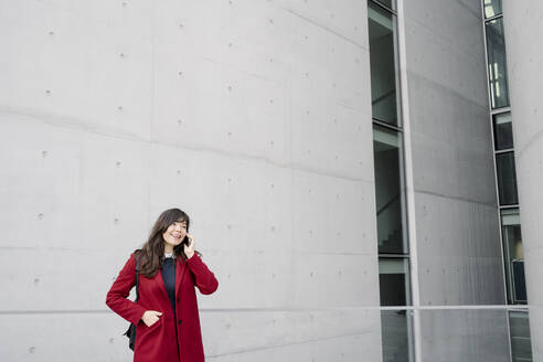 Geschäftsfrau steht in der Nähe eines modernen Gebäudes und benutzt ein Smartphone - AHSF01526