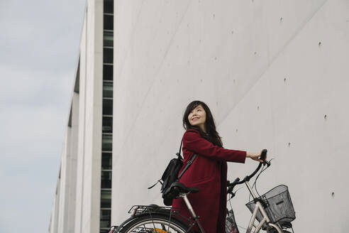 Geschäftsfrau nimmt Fahrrad im Hintergrund des modernen Gebäudes - AHSF01528