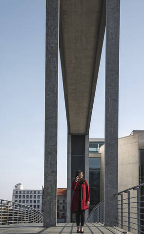 Geschäftsfrau, die auf einer Brücke geht und ein Smartphone benutzt, lizenzfreies Stockfoto