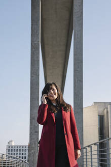 Geschäftsfrau steht in der Nähe eines modernen Gebäudes und benutzt ein Smartphone - AHSF01541