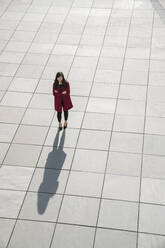 Blick von oben auf eine gehende moderne Geschäftsfrau, die auf einem Betonboden steht - AHSF01543