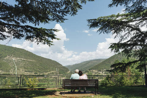 Rückenansicht eines älteren Paares, das auf einer Bank sitzt und die Aussicht betrachtet, Jaca, Spanien, lizenzfreies Stockfoto