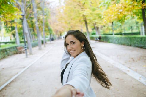 Porträt einer lächelnden Frau im Park, die Hand in Hand geht - KIJF02828