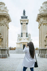 Frau fotografiert das Alfonso XII-Denkmal im Park El Retiro, Madrid, Spanien - KIJF02831