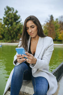 Frau benutzt ihr Smartphone in einem Park - KIJF02839