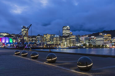 Neuseeland, Wellington, Lichtkugeln entlang des Hafens bei Nacht mit beleuchteter Stadtsilhouette im Hintergrund - FOF11261