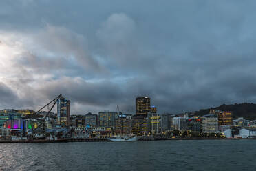 New Zealand, Wellington, Clouds over waterfront city skyline at dusk - FOF11267