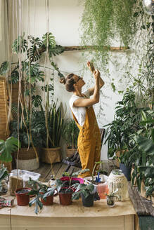 Young woman caring for plants in a small shop - VPIF01836