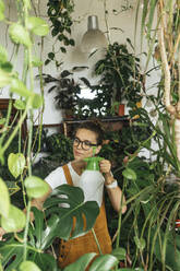 Young woman caring for plants in a small shop - VPIF01847