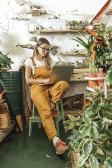 Junge Frau mit Laptop in einer kleinen Gärtnerei - VPIF01851