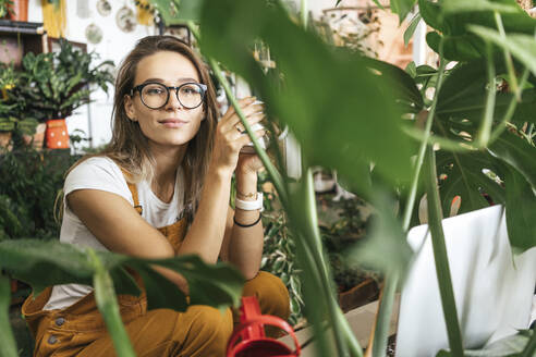Porträt einer jungen Frau bei einer Kaffeepause in einer kleinen Gärtnerei - VPIF01858