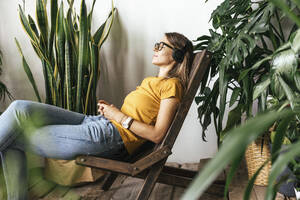 Relaxed young womansitting in chair listening to music at home - VPIF01869