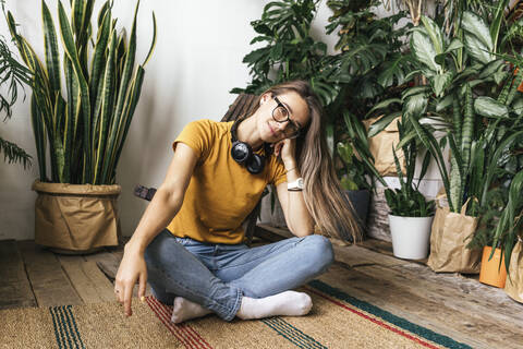 Porträt einer entspannten jungen Frau, die zu Hause auf dem Boden sitzt, lizenzfreies Stockfoto