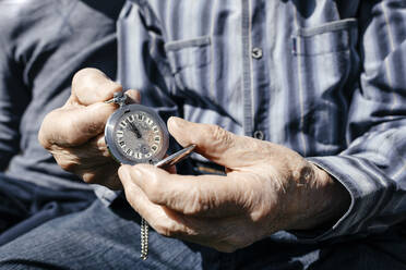 Old man's hands holding silver pocket clock, close-up - EYAF00710