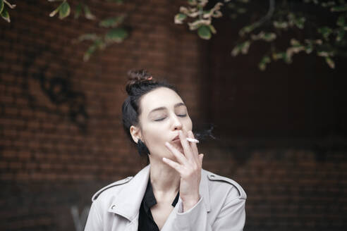 Portrait of woman smoking with eyes closed - EYAF00712