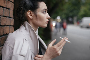 Profil einer nachdenklichen Frau mit Zigarette im Freien - EYAF00713