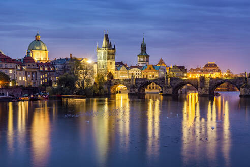 Czech Republic, Prague, Birds swimming in Vltava river at dusk with Charles Bridge and Old Town of Prague in background - YRF00219