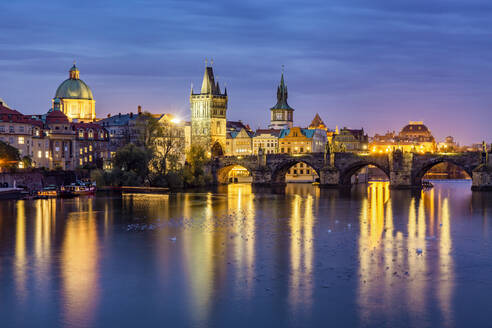 Tschechische Republik, Prag, Vögel schwimmen in der Moldau in der Abenddämmerung mit Karlsbrücke und Altstadt von Prag im Hintergrund - YRF00219