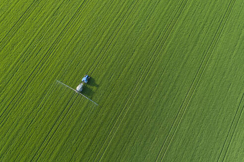 Deutschland, Thüringen, Luftaufnahme einer Pflanzenschutzspritze in einem grünen Feld - RUEF02391