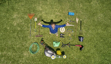 Blick von oben auf einen Gärtner auf einer Wiese stehend mit allen Werkzeugen, die er zur Pflege des Gartens benötigt - VEGF00989