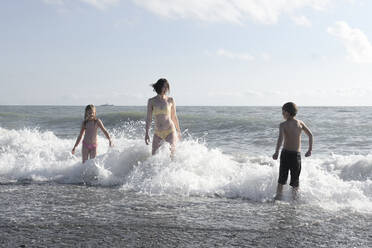 Glückliche Mutter mit zwei Kindern, die sich im Meer vergnügen - EYAF00719