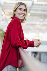 Porträt einer lächelnden jungen Geschäftsfrau, die an einem Geländer steht - DIGF08991