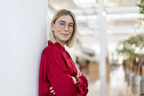 Portrait of a confident young businesswoman leaning against a column - DIGF08994