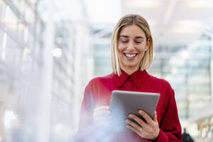 Glückliche junge Geschäftsfrau im roten Hemd mit Tablet - DIGF09006