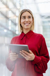 Lächelnde junge Geschäftsfrau in rotem Hemd mit Tablet - DIGF09008
