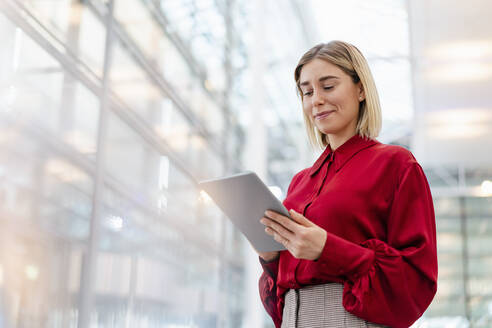 Young businesswoman wearing red shirt using tablet - DIGF09009