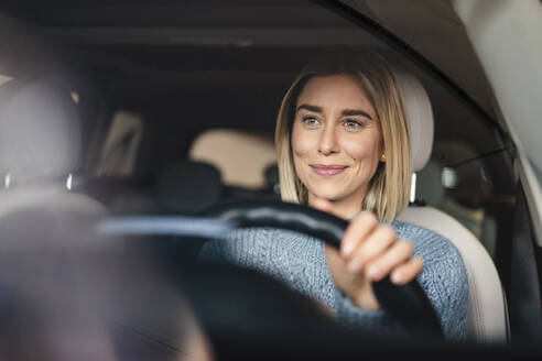 Portrait of smiling young woman driving a car - DIGF09018