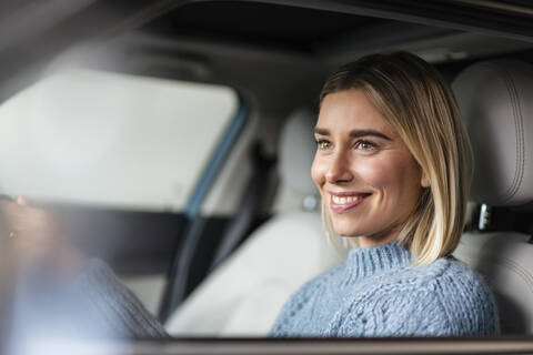 Porträt einer lächelnden jungen Frau am Steuer eines Autos, lizenzfreies Stockfoto