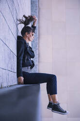 Woman with sunglasses sitting on ledge - DHEF00010