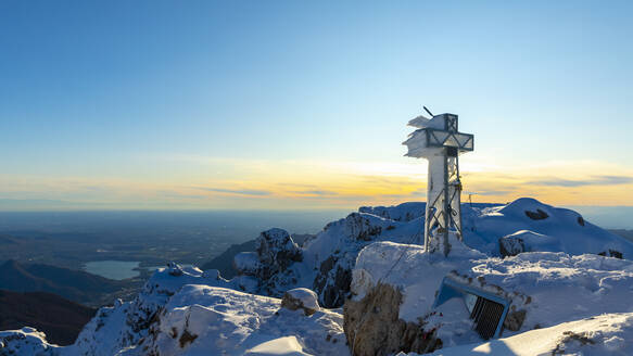 Blick über verschneite Berge mit einem gefrorenen Gipfelkreuz, Lecco, Italien - MCVF00092