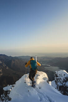 Bergsteiger, der den Gipfel eines verschneiten Berges erreicht und die Aussicht genießt, Lecco, Italien - MCVF00094