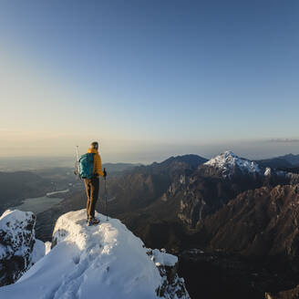 Bergsteiger, der auf dem Gipfel eines verschneiten Berges steht und die Aussicht genießt, Lecco, Italien - MCVF00095