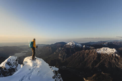 Bergsteiger, der auf dem Gipfel eines verschneiten Berges steht und die Aussicht genießt, Lecco, Italien - MCVF00096