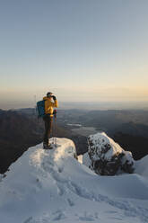 Mountaineer standing on top of a snowy mountain enjoying the view, Lecco, Italy - MCVF00097