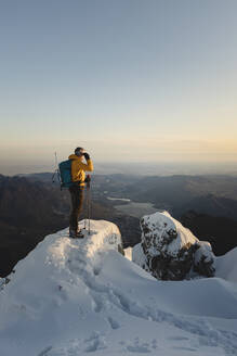 Bergsteiger, der auf dem Gipfel eines verschneiten Berges steht und die Aussicht genießt, Lecco, Italien - MCVF00097