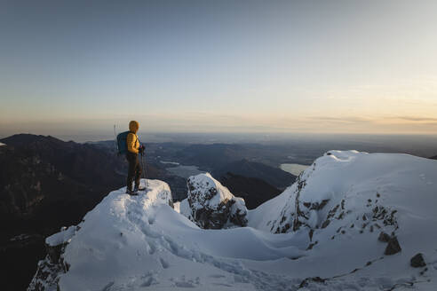 Bergsteiger, der auf dem Gipfel eines verschneiten Berges steht und die Aussicht genießt, Lecco, Italien - MCVF00098