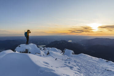 Mountaineer standing on top of a snowy mountain enjoying the view, Lecco, Italy - MCVF00101