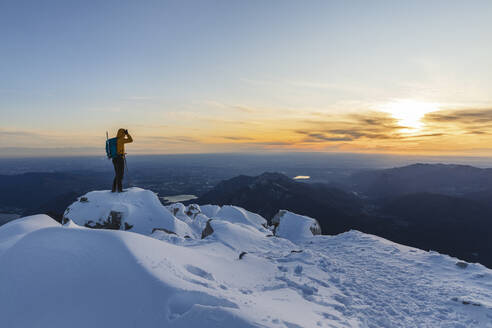 Bergsteiger, der auf dem Gipfel eines verschneiten Berges steht und die Aussicht genießt, Lecco, Italien - MCVF00101