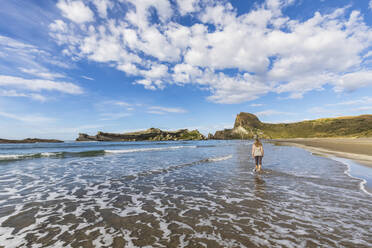 Neuseeland, Region Wellington, Castlepoint, Frau geht am Sandstrand des Pazifischen Ozeans entlang - FOF11332