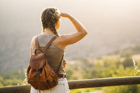 Frau mit Lederrucksack schaut auf Aussicht, lizenzfreies Stockfoto