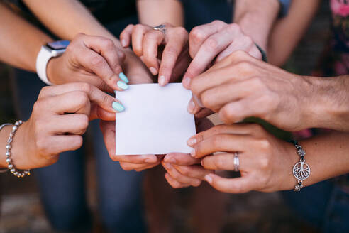 Close-up of friends holding a blank card - MPPF00369