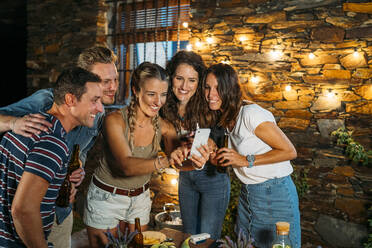 Happy friends meeting outdoors at a stone house taking a selfie - MPPF00372