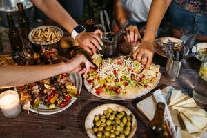 Nahaufnahme von Freunden, die bei einem Abendessen im Freien essen - MPPF00375